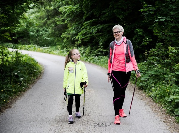 kobieta i dziewczynka idą droga z kijami do nordic walking