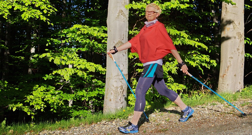 kobieta idąca leśną ścieżką krokiem nordic walking